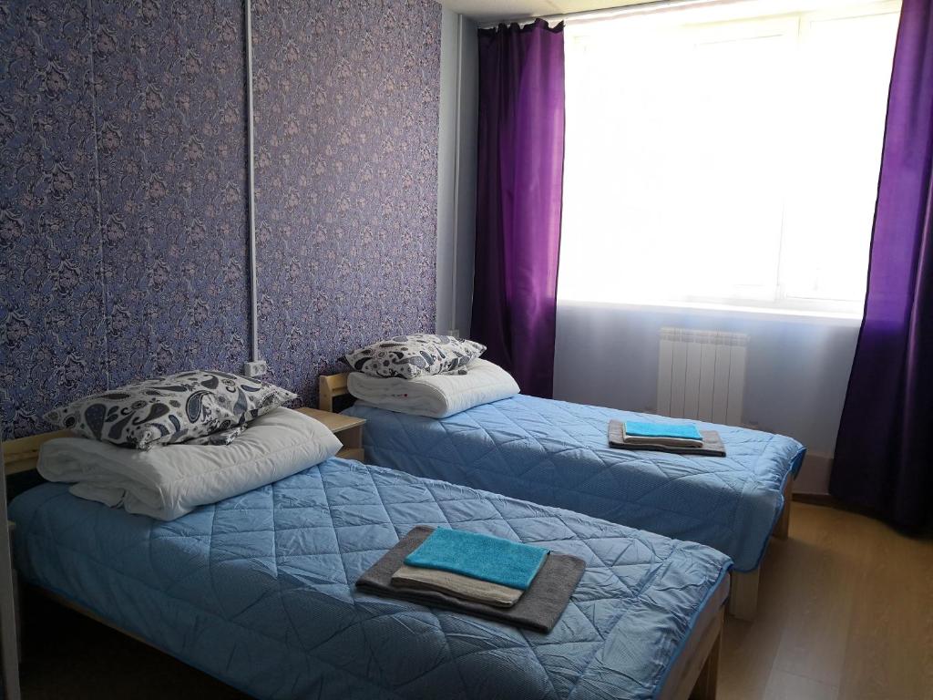 セヴェロバイカリスクにあるHostel03RUSの紫の壁と窓が特徴の客室で、ベッド2台が備わります。