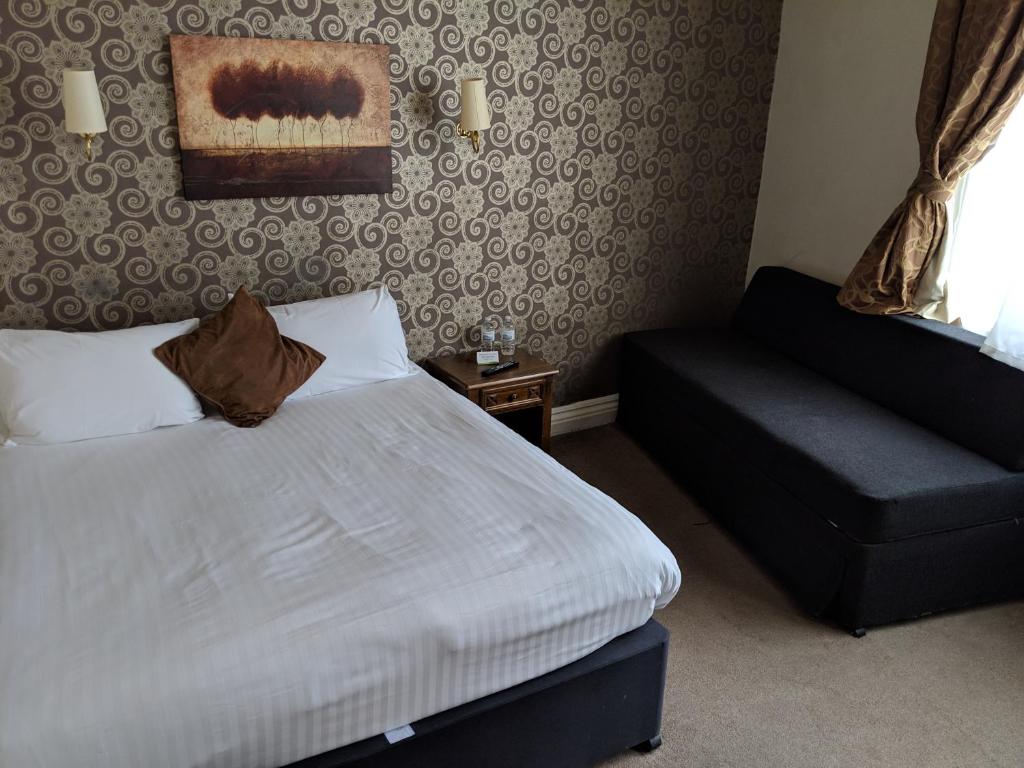 a bedroom with a bed and a chair and a window at White Hart, Andover by Marston's Inns in Andover