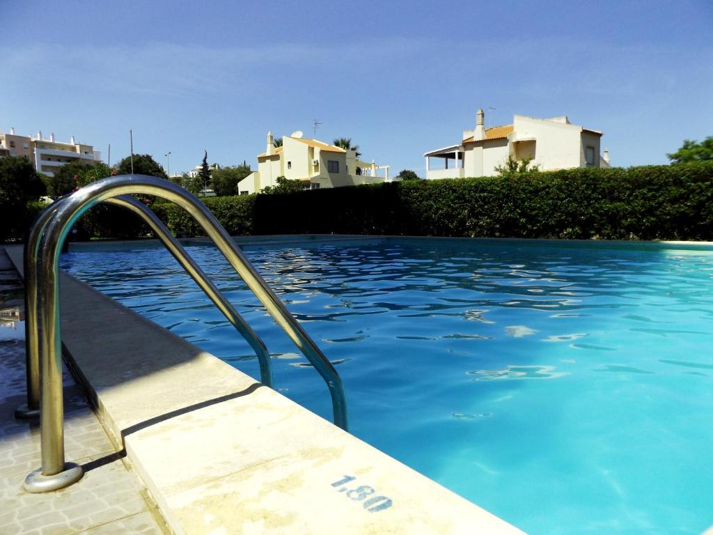 a swimming pool with a metal handrail in front of some houses at Sunny apartamento in Portimão