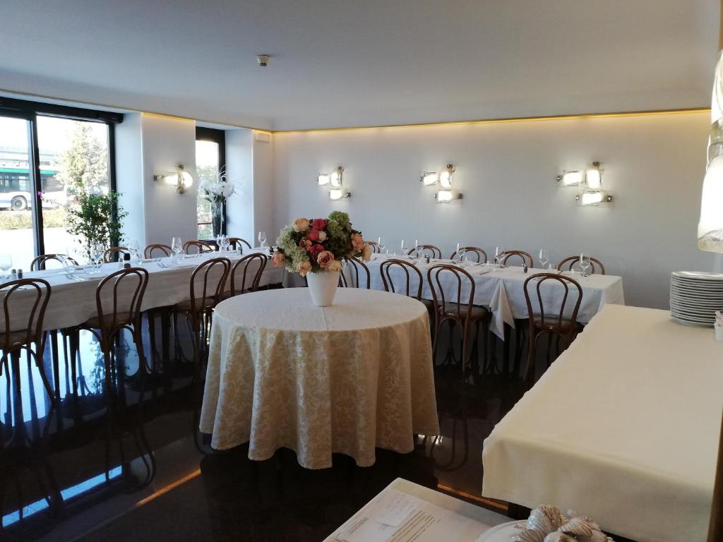 a room with tables and chairs with a vase of flowers at Hotel Belvedere in Venice-Lido