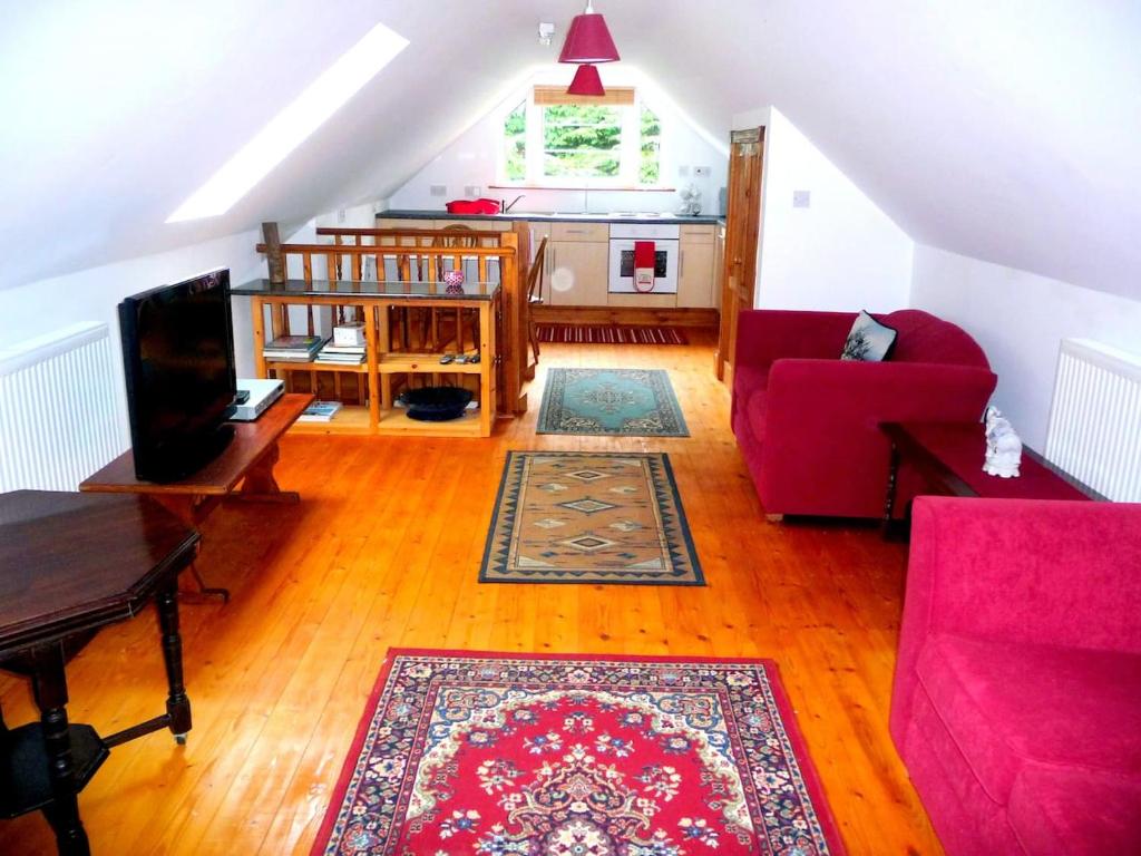 ein Wohnzimmer mit einem roten Sofa und einem Teppich in der Unterkunft Croft Flat in Kilgetty