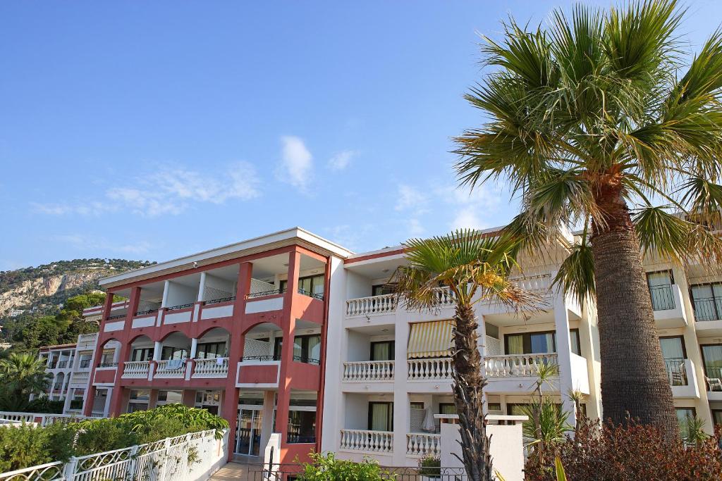 a building with palm trees in front of it at Résidence Pierre & Vacances l'Ange Gardien in Villefranche-sur-Mer