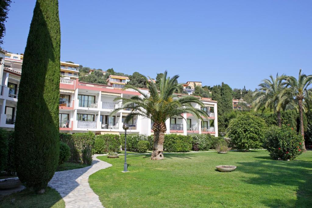 a large building with a palm tree in a park at Résidence Pierre & Vacances l'Ange Gardien in Villefranche-sur-Mer