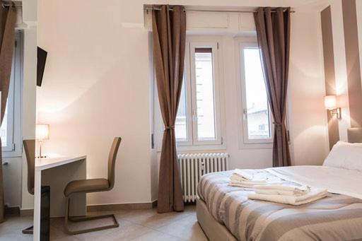 a bedroom with a bed and a desk and a window at MINERVA GUEST HOUSE in Pavia