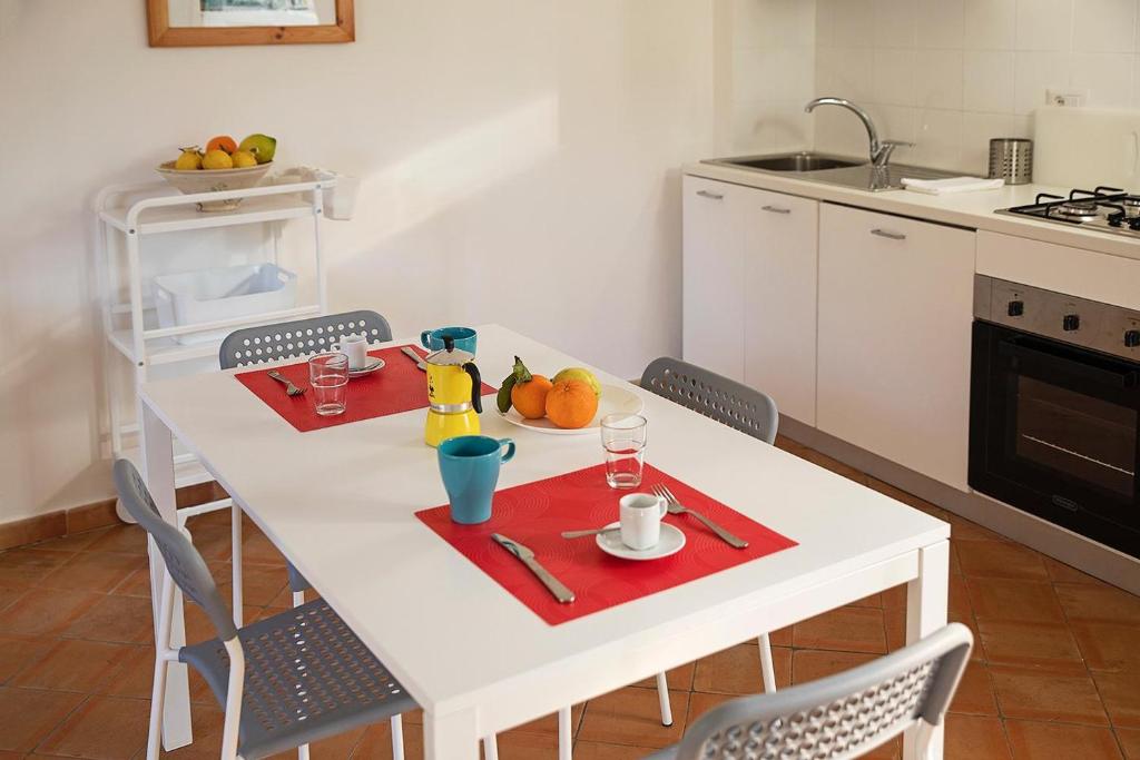 cocina con mesa blanca y 2 servilletas rojas en San Pietro Holiday House en Scala