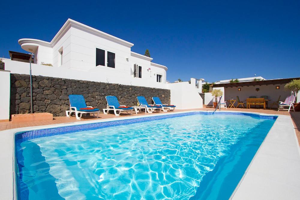 ein Pool mit blauen Stühlen und ein Haus in der Unterkunft Casa McElroy in Tías