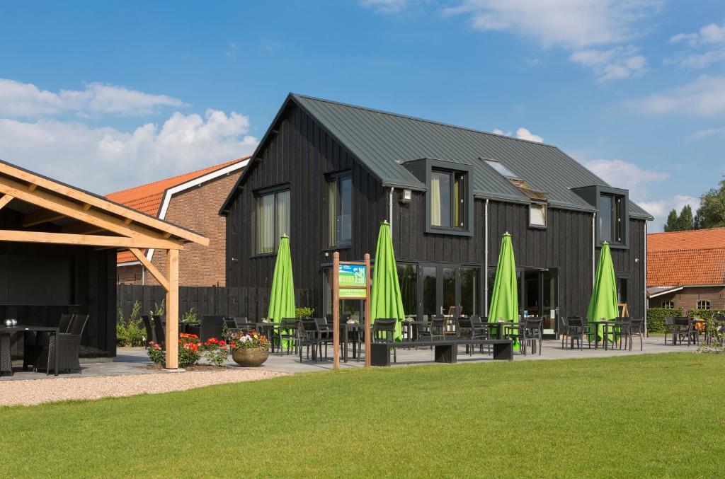 ein schwarzes Gebäude mit Tischen, Stühlen und Sonnenschirmen in der Unterkunft B&B Restaurant Maria Johanna Hoeve in Noordeloos