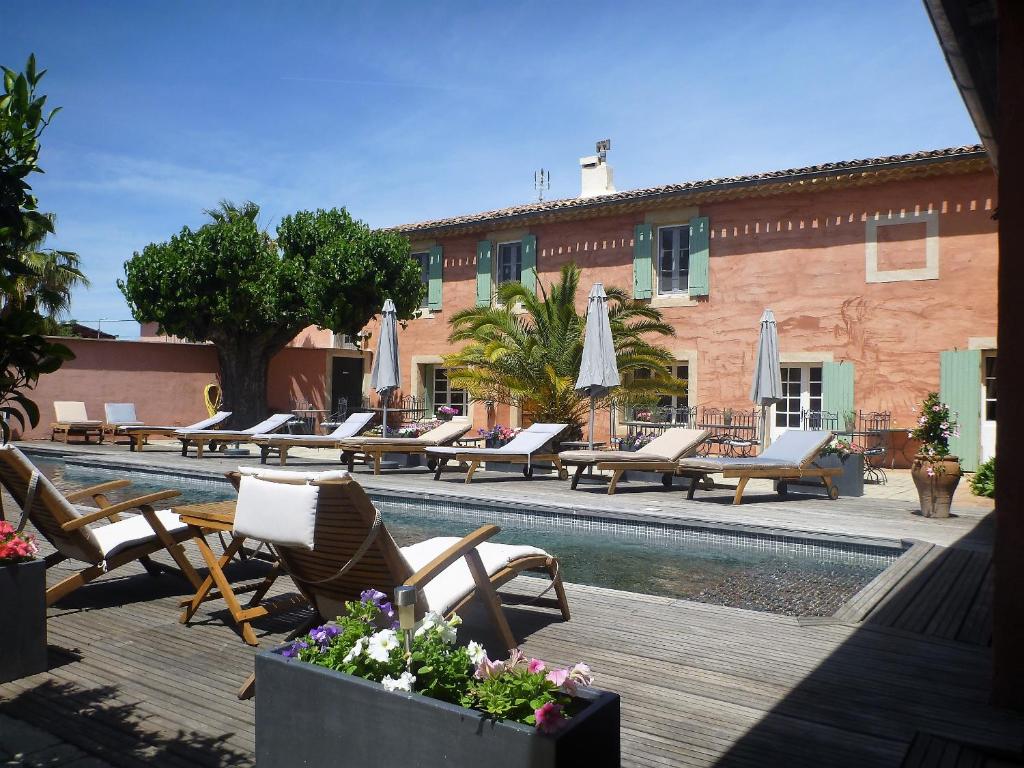 a pool with chairs and umbrellas next to a building at Le Mas De Gleyzes B&B de Charme in Lédenon