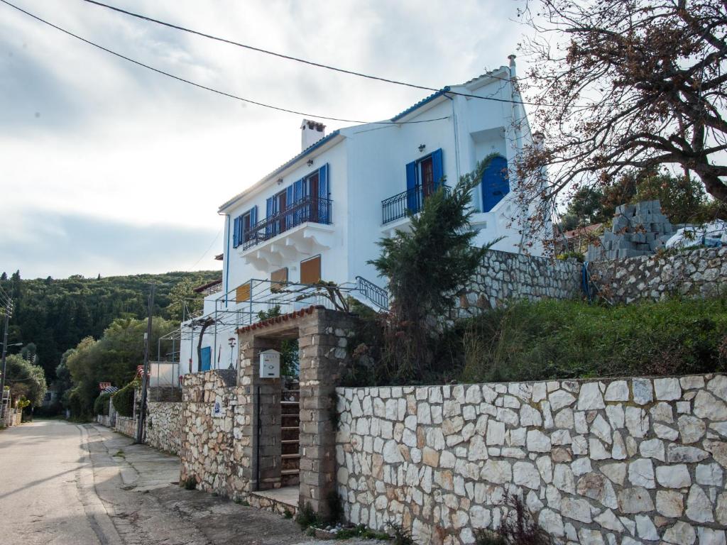 una casa bianca su una collina con un muro di pietra di Fey's House waterfront - Φισκάρδο a Fiskardho
