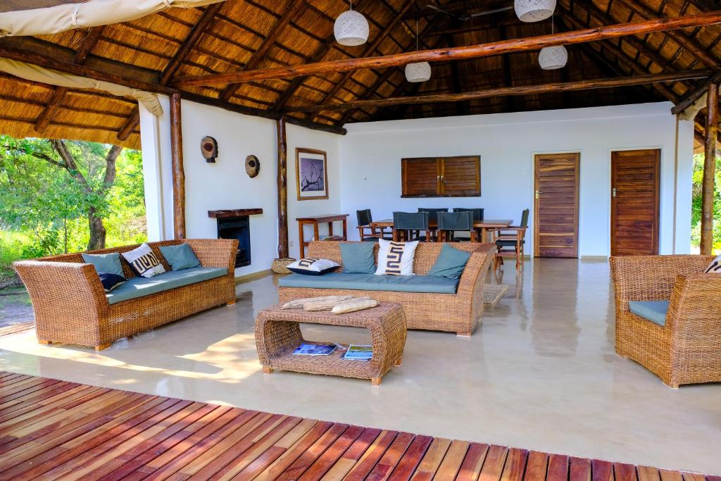 a living room with wicker furniture and a fireplace at DOMUS - Private Bush Camp in Lusaka