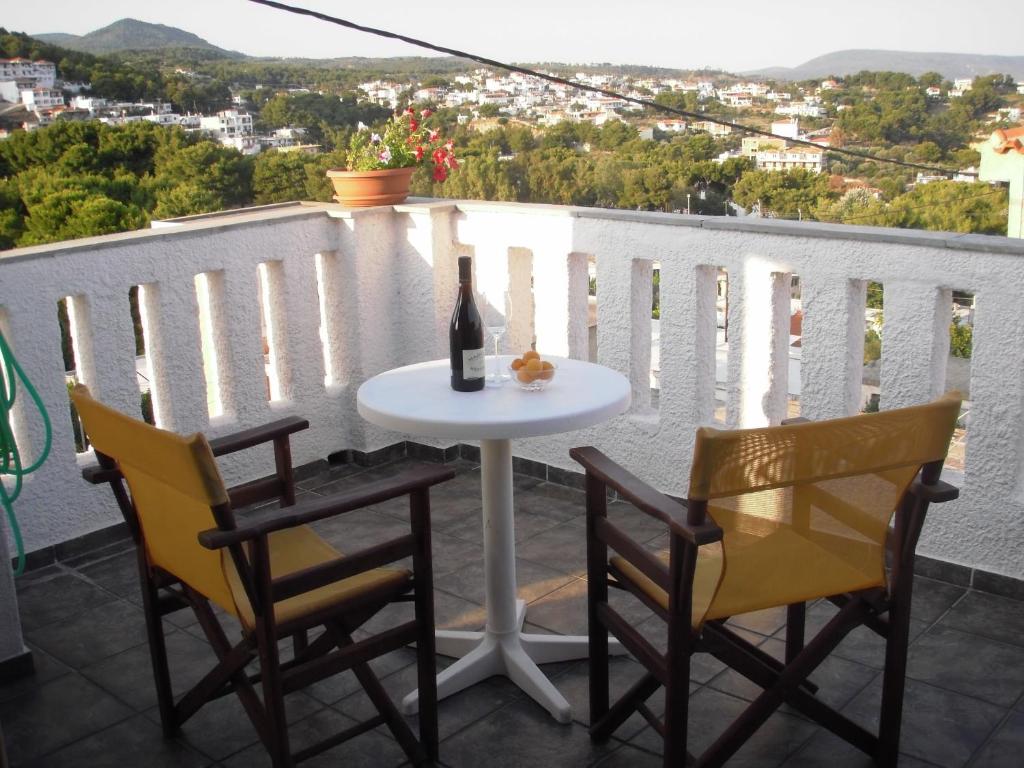 un tavolo con 2 sedie e una bottiglia di vino sul balcone di Ikos Studios and Apartments a Patitiri