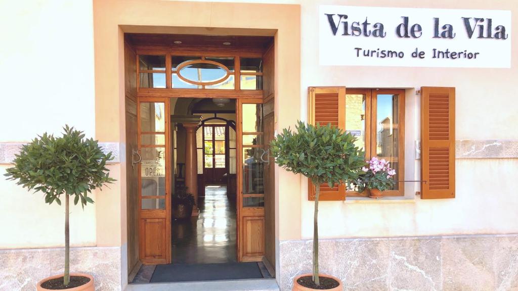 une porte menant à un bâtiment avec deux usines devant lui dans l'établissement Vista de la Vila - Turismo de interior., à Llubí