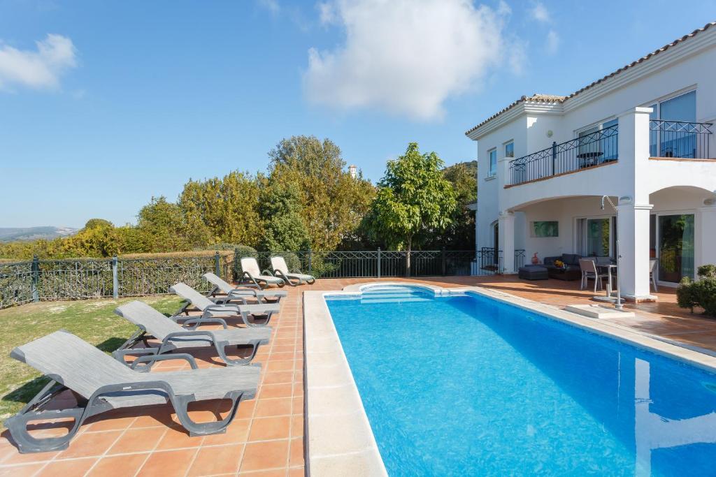 a villa with a swimming pool and lounge chairs at Arcos Gardens Sol Rent Golf in Arcos de la Frontera