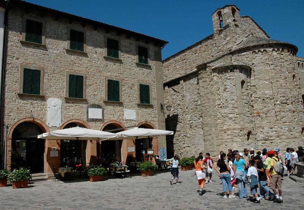 Un gruppo di persone che camminano davanti a un edificio di San Leo Albergo Diffuso a San Leo