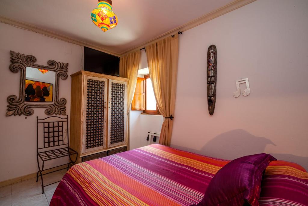 a bedroom with a bed with a colorful blanket at Hostal El Asturiano in Tarifa