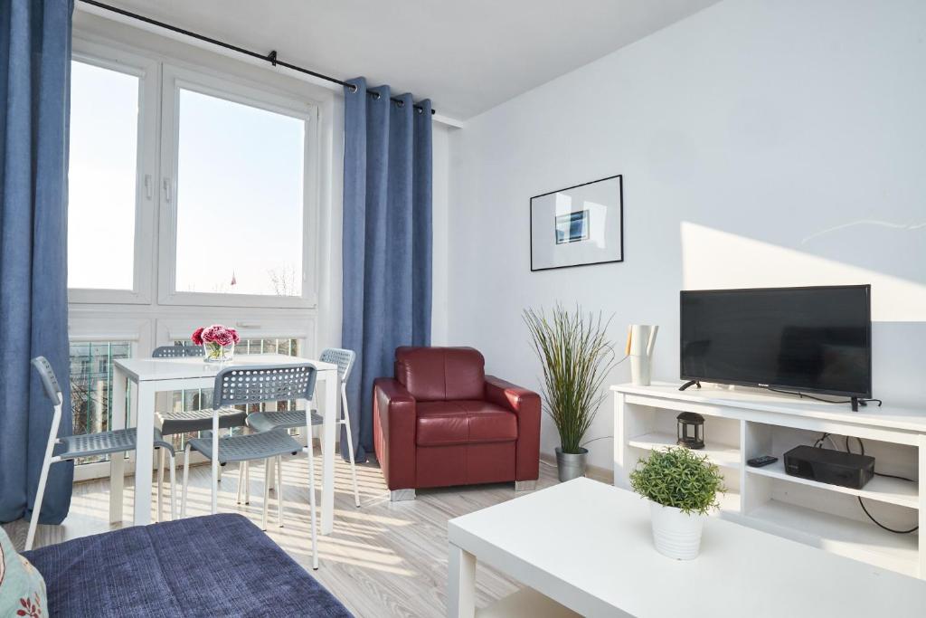ワルシャワにあるNoctis Apartment Senatorskaのリビングルーム(赤い椅子、テレビ付)