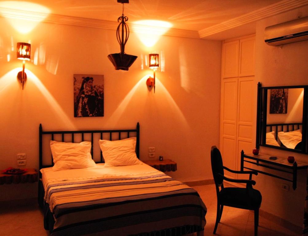 1 dormitorio con cama, silla y luces en Résidence Le Ruisseau, en Tozeur