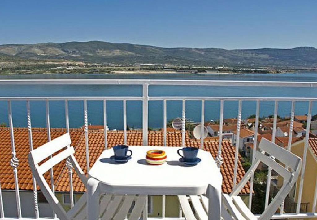 een tafel en stoelen op een balkon met uitzicht op het water bij Apartments Hazi 1 - 150m from sea in Trogir