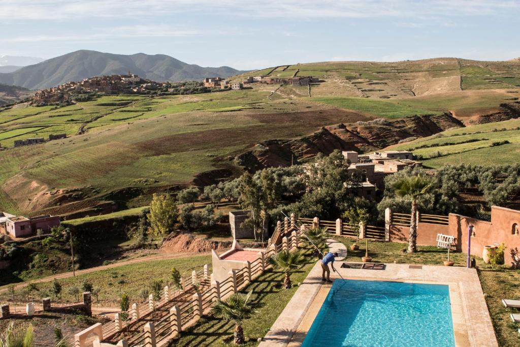 a man standing next to a swimming pool in a mountain at Tigmi Nomade in Tahannout