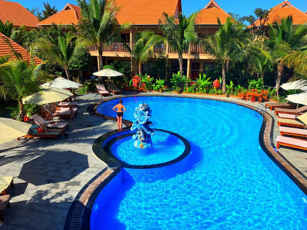 una persona in piedi di fronte alla piscina di un resort di Golden Topaz Phu Quoc Resort a Phu Quoc