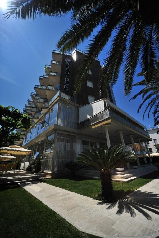 a building with a palm tree in front of it at Hotel President in Alba Adriatica