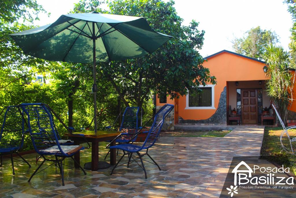una mesa y sillas con una sombrilla en el patio en Posada Basiliza, Encarnación PY, en Encarnación