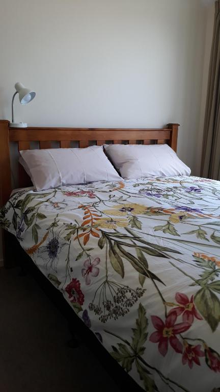 een bed met een deken met bloemen erop bij 201Waimumu in Gore