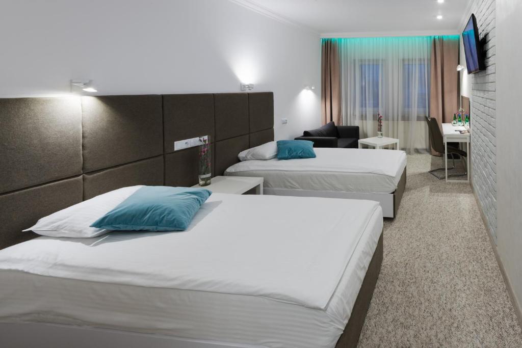 プシェジミエロボにあるGLAMOUR - Restaurant & SPAのベッド2台とデスクが備わるホテルルームです。