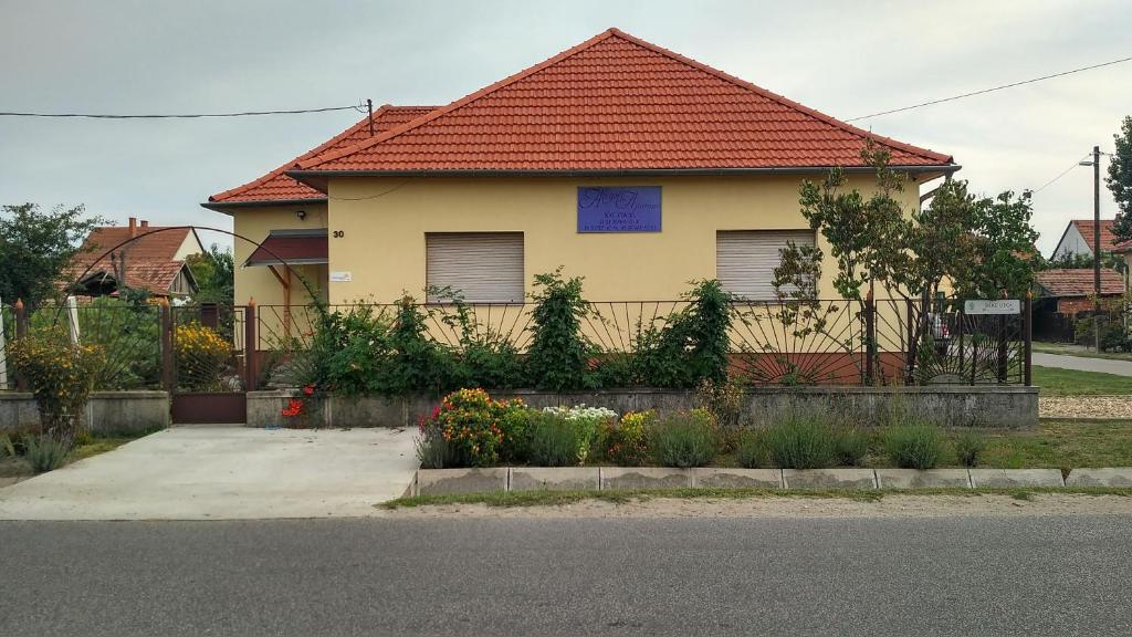 una casa amarilla con techo rojo en Abigél Apartman en Mórahalom