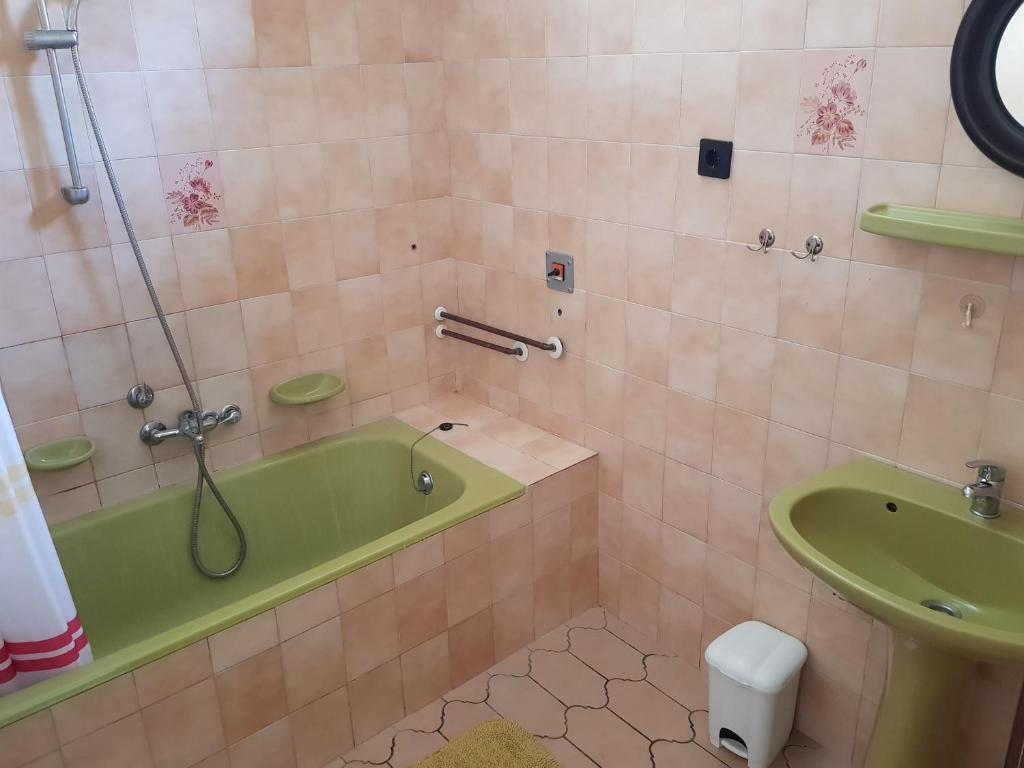 "ハルカーニャ"にあるÁgnes Apartmanokのバスルーム(緑のバスタブ、シンク付)