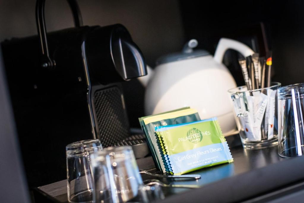 a table with glasses and a tea kettle and a book at Hôtel Daria-I Nor by Les Etincelles in L'Alpe-d'Huez