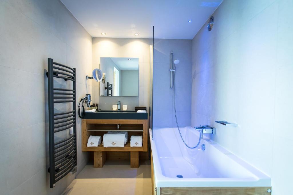a bathroom with a tub and a sink and a mirror at Hôtel Daria-I Nor by Les Etincelles in L'Alpe-d'Huez