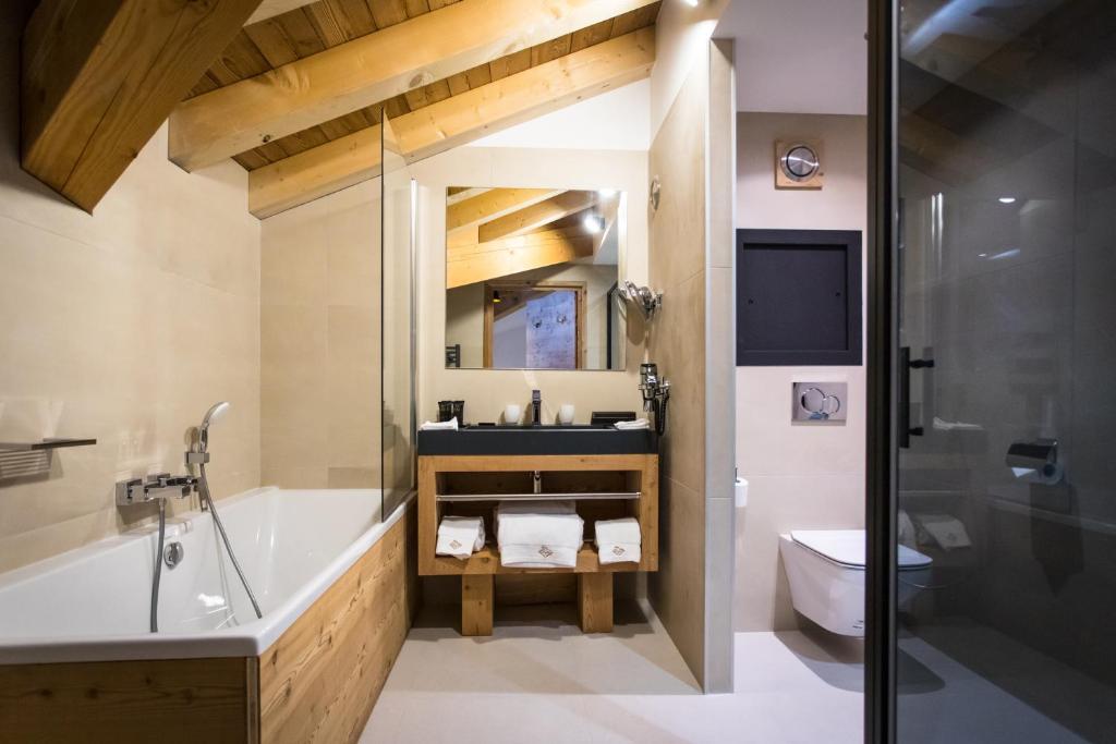 a bathroom with a tub and a sink and a toilet at Hôtel Daria-I Nor by Les Etincelles in L'Alpe-d'Huez