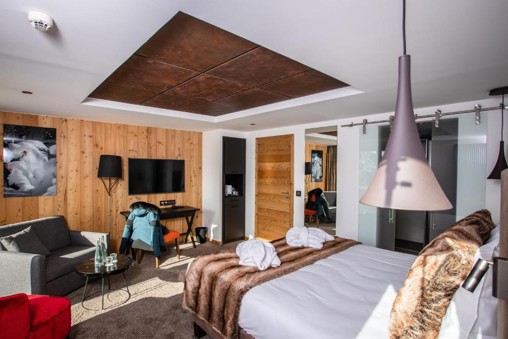 a bedroom with a bed and a living room at Hôtel Daria-I Nor by Les Etincelles in L'Alpe-d'Huez