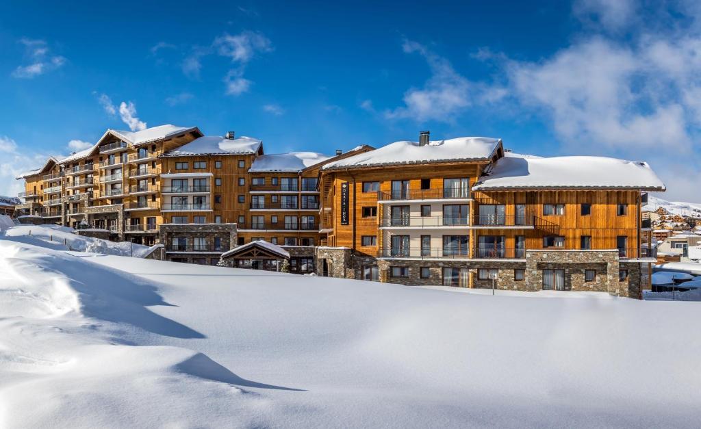 een resort in de sneeuw met besneeuwde gebouwen bij Hôtel Daria-I Nor by Les Etincelles in L'Alpe-d'Huez