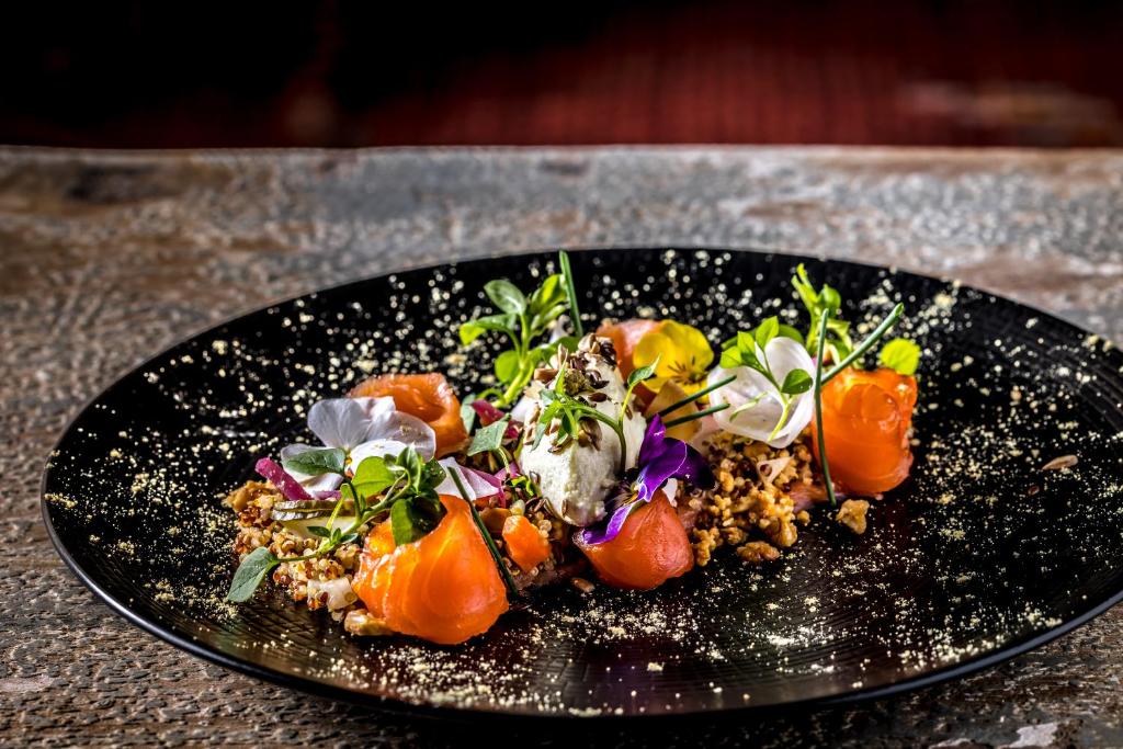 a black plate of food on a table at Hôtel Daria-I Nor by Les Etincelles in L'Alpe-d'Huez