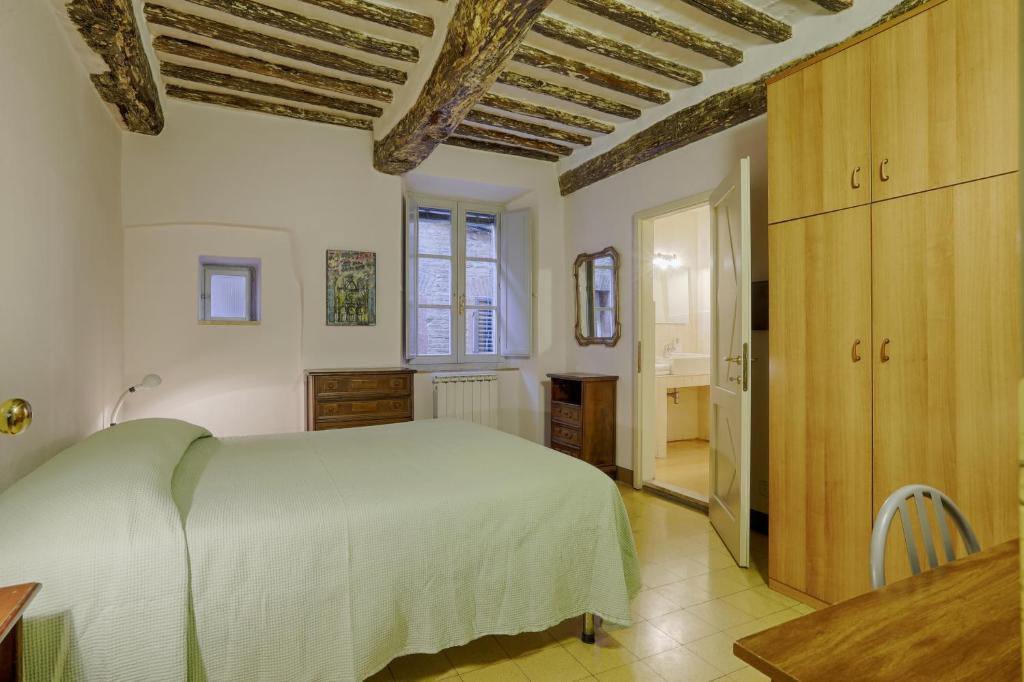 a bedroom with a white bed and wooden ceilings at Attilio Camere in Siena