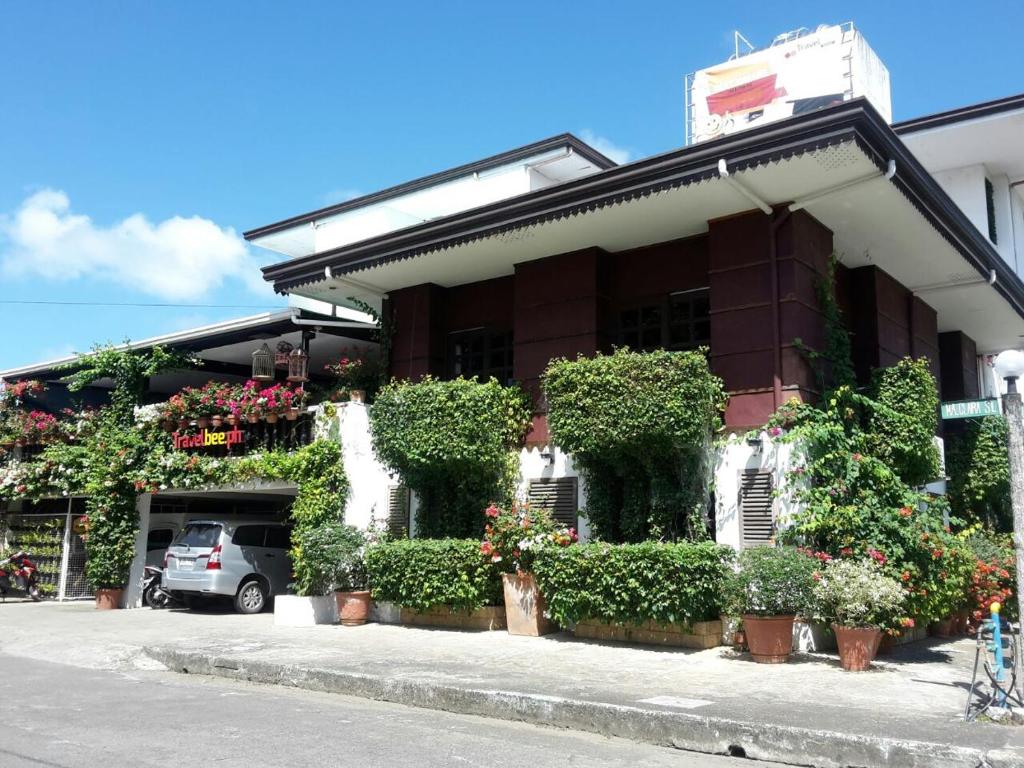 a building with plants and flowers in front of it at Travelbee Heritage Inn in Dapitan