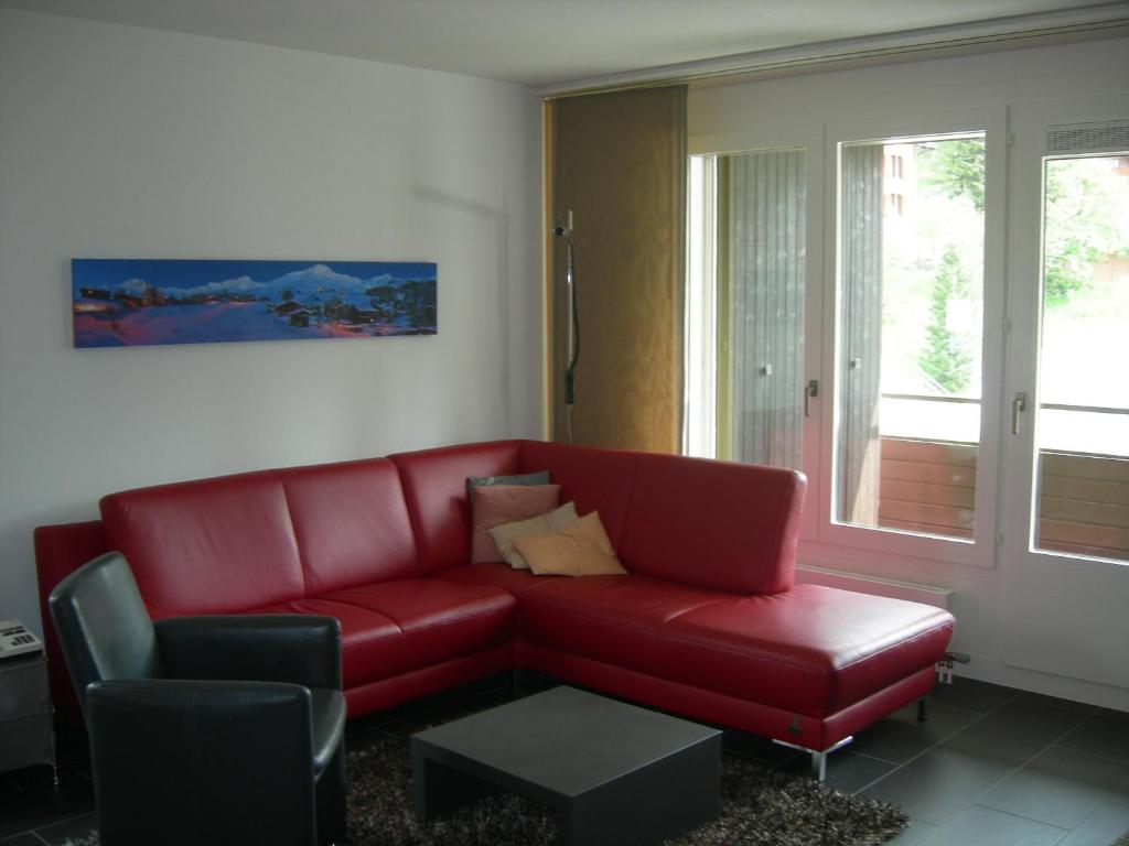 czerwona kanapa i krzesło w salonie w obiekcie Brüggli A14 w mieście Arosa