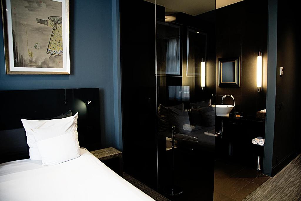 a black room with a bed and a bathroom at Hotel Les Nuits in Antwerp