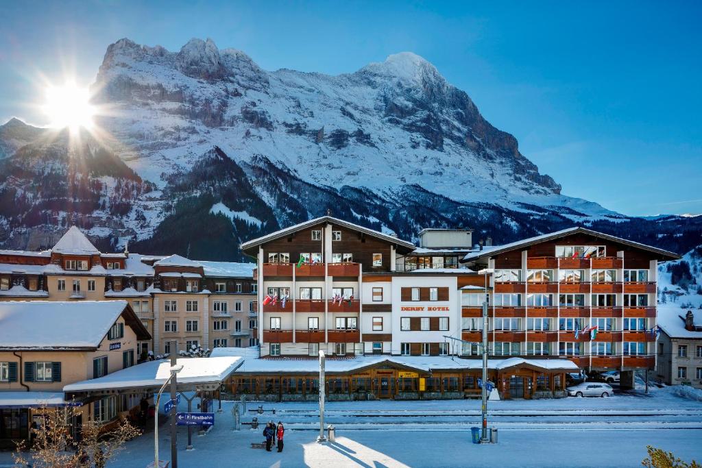 a hotel with a snow covered mountain in the background at Derby Swiss Quality Hotel in Grindelwald