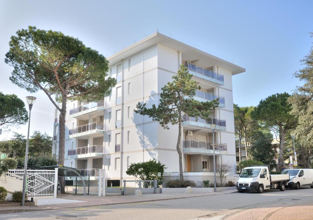 a white building with cars parked in front of it at Condominio Delfino in Bibione