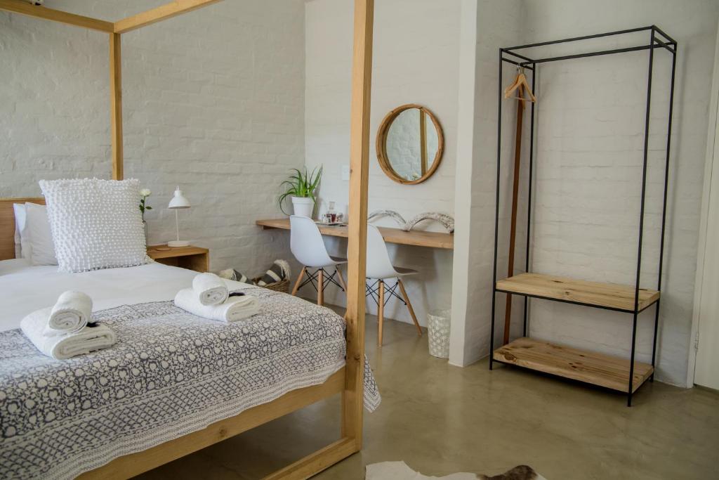 a bedroom with a bed and a desk and a mirror at Raw Karoo Guest House in Oudtshoorn