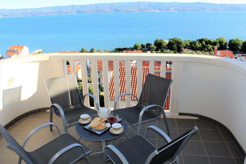 a balcony with chairs and a table with food on it at Apartmani Marija in Duće