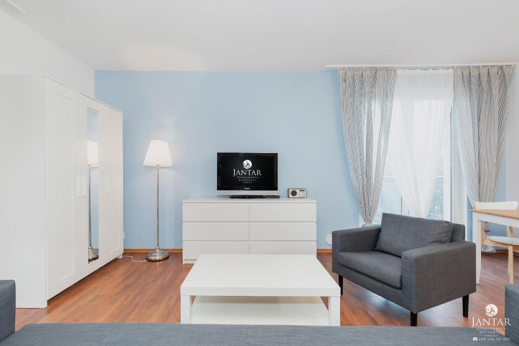 a living room with a couch and a chair at Jantar Apartamenty - Promenada Kołobrzeg in Kołobrzeg