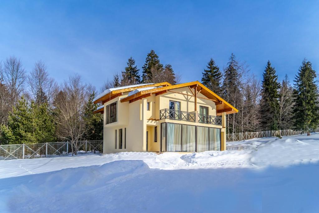 a house in the snow with a fence at Villa by Sunexpress Bakuriani in Bakuriani