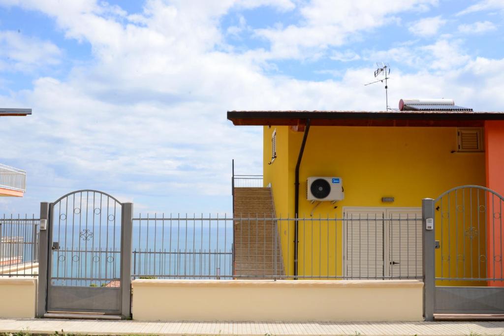 a yellow building with a gate and a fence at Jonico Guest house .. calabria in Montegiordano