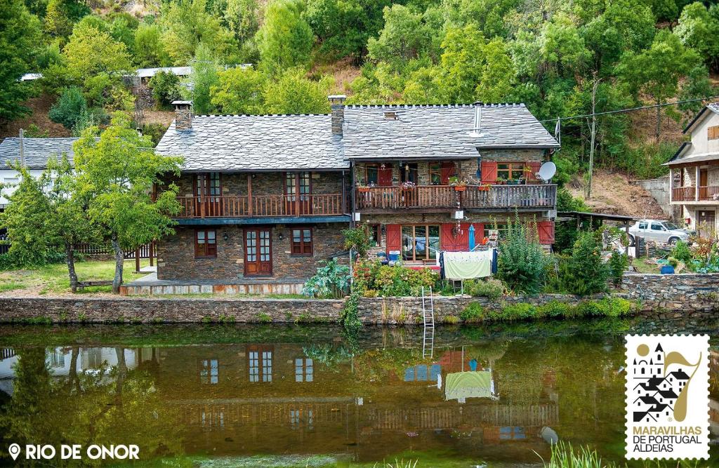 a large house sitting on the side of a river at Casa da Ponte Rio de Onor in Bragança