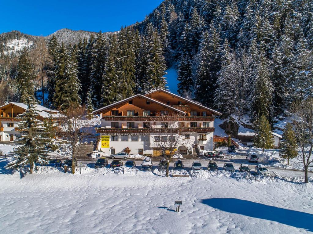 un lodge en la nieve frente a una montaña en Hotel Pontives en Ortisei