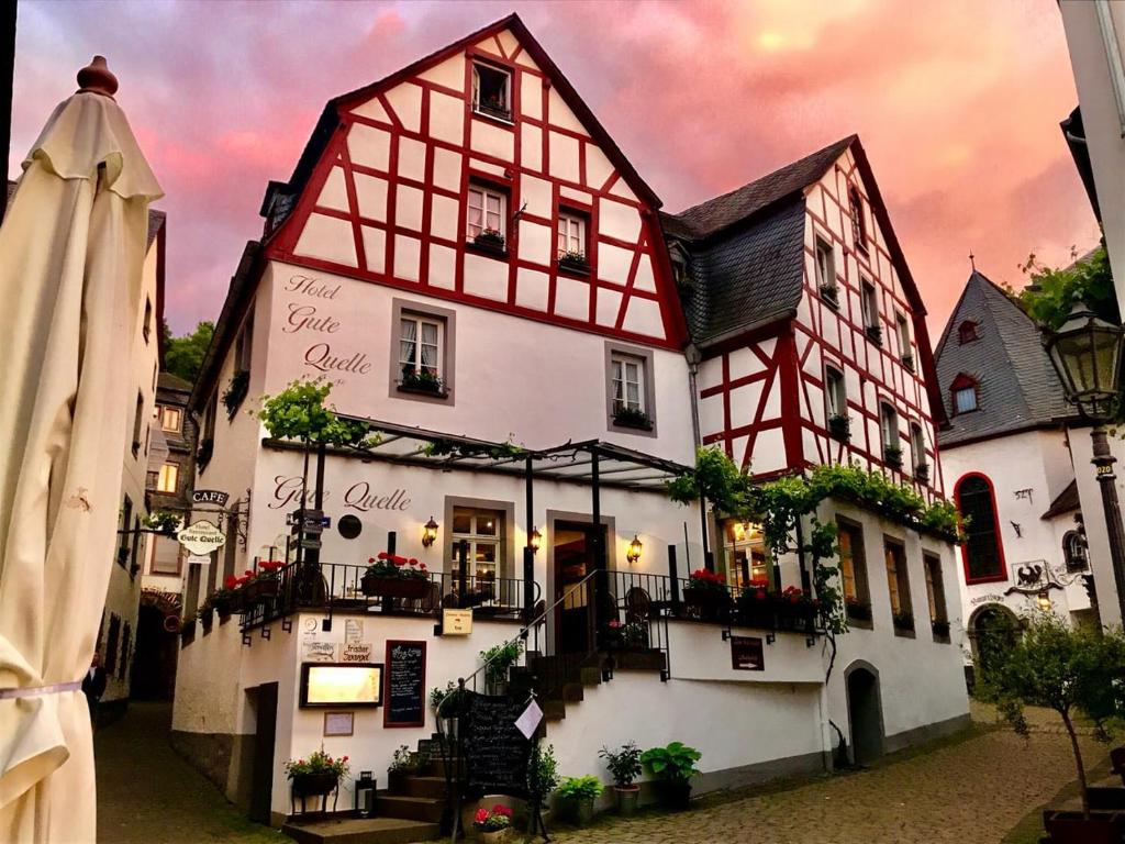 un edificio blanco y rojo con flores delante en Hotel Gute Quelle en Beilstein